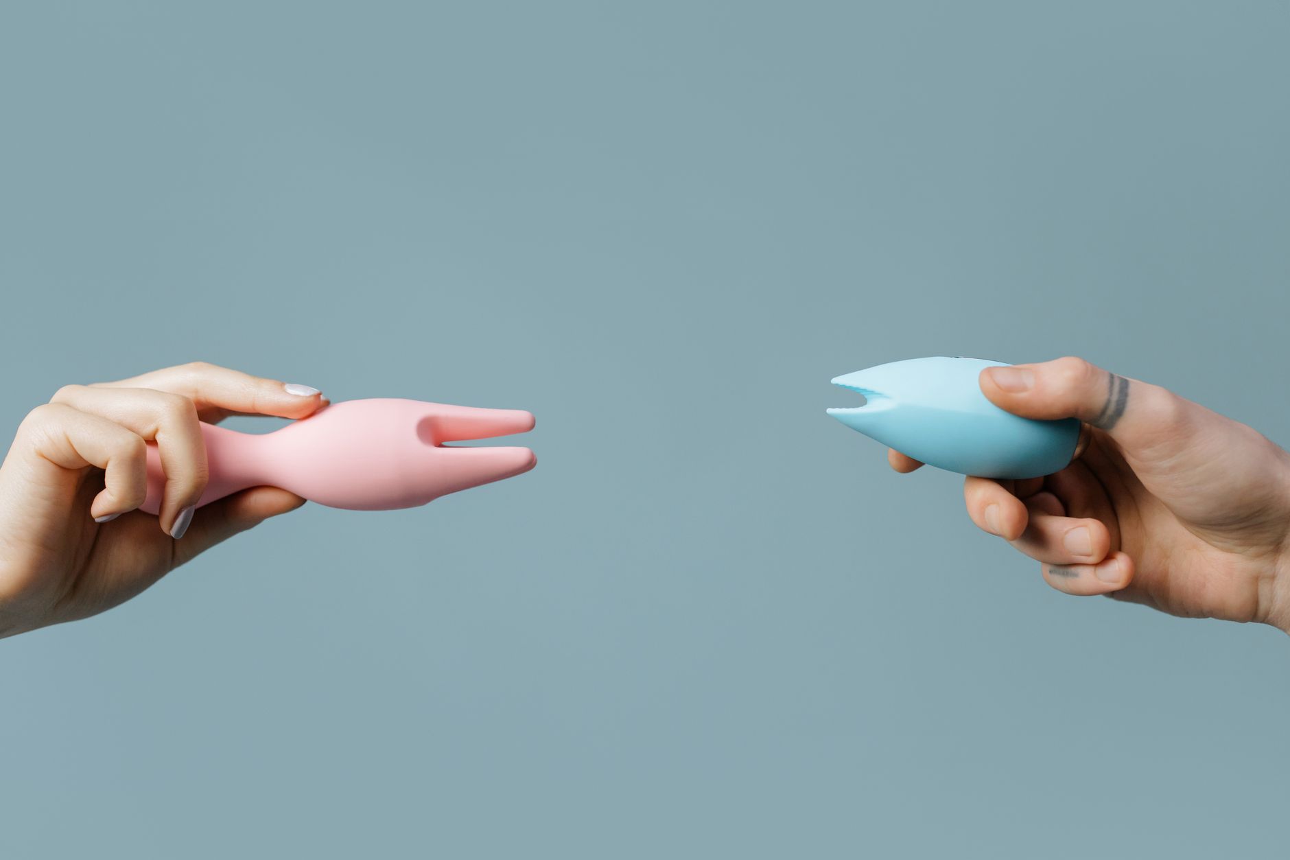 Close-up of hands holding a sleek vibrator, representing intimacy and connection between partners